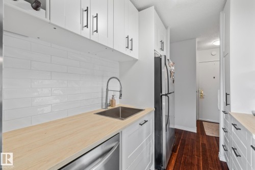 Kitchen with white cabinets, stainless steel appliances, light countertops, dark wood-type flooring, and a textured ceiling - 1502 9909 110 Street, Edmonton, AB - Indoor Photo Showing Kitchen