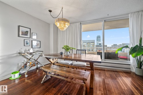 Dining room featuring dark wood-style floors, a textured ceiling, a chandelier, and a view of city - 1502 9909 110 Street, Edmonton, AB - Indoor Photo Showing Dining Room