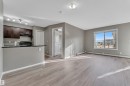 Unfurnished living room featuring light wood-type flooring, a textured ceiling, and baseboard heating - 216 5804 Mullen Place, Edmonton, AB  - Indoor Photo Showing Kitchen 