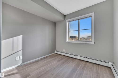 Empty room with a baseboard heating unit and light wood-style floors - 216 5804 Mullen Place, Edmonton, AB - Indoor Photo Showing Other Room