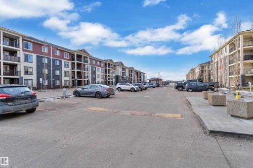 View of asphalt street with a speed bump, curbs, and sidewalks - 216 5804 Mullen Place, Edmonton, AB - Outdoor With Balcony With Facade