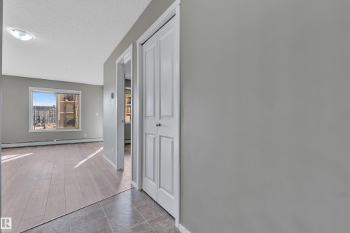 Hallway with baseboard heating, a textured ceiling, and wood finished floors - 216 5804 Mullen Place, Edmonton, AB - Indoor Photo Showing Other Room
