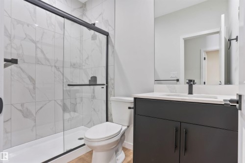 Full bath featuring a marble finish shower, vanity, and light wood-style flooring - 116 25 Street, Edmonton, AB - Indoor Photo Showing Bathroom