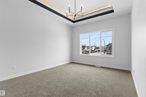 Carpeted empty room with a tray ceiling and suspended lighting - 116 25 Street, Edmonton, AB - Indoor Photo Showing Other Room
