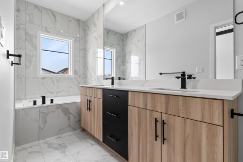 Bathroom with double vanity, a bath, and light marble finish flooring - 116 25 Street, Edmonton, AB - Indoor Photo Showing Bathroom