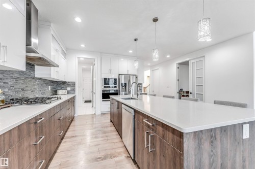 Kitchen with two tone cabinets, modern cabinets, decorative light fixtures, light wood-style flooring, and stainless steel appliances - 1407 Graydon Hill Way, Edmonton, AB - Indoor Photo Showing Kitchen With Upgraded Kitchen