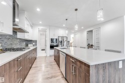 Kitchen with two tone cabinets, modern cabinets, decorative light fixtures, light wood-style flooring, and stainless steel appliances - 