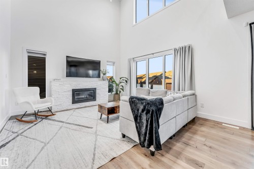 Living room featuring light wood-style floors, a fireplace, and a high ceiling - 1407 Graydon Hill Way, Edmonton, AB - Indoor Photo Showing Living Room With Fireplace