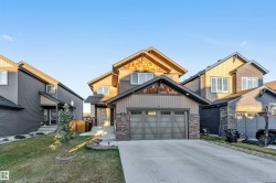 Craftsman-style home with concrete driveway, board and batten siding, an attached garage, stone siding, and a front lawn - 