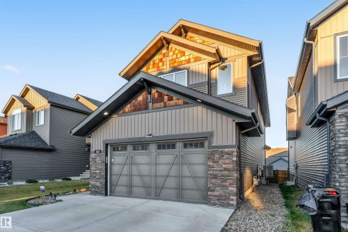 View of front facade with board and batten siding, concrete driveway, stone siding, and an attached garage - 1407 Graydon Hill Way, Edmonton, AB - Outdoor