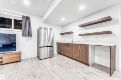 Kitchen with freestanding refrigerator, open shelves, light wood-style flooring, modern cabinets, and recessed lighting - 