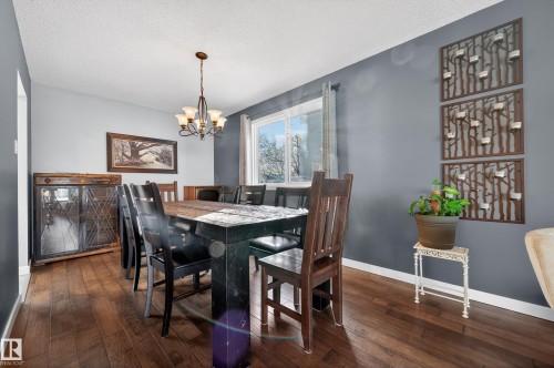 Dining area featuring dark wood finished floors, hanging lights, and a textured ceiling - 9215 Ottewell Road, Edmonton, AB - Indoor Photo Showing Dining Room
