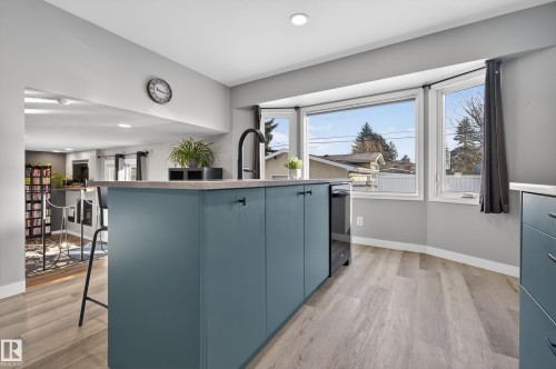 Kitchen with a center island with sink, light wood finished floors, a kitchen bar, recessed lighting, and stainless steel dishwasher - 9215 Ottewell Road, Edmonton, AB - Indoor Photo Showing Kitchen
