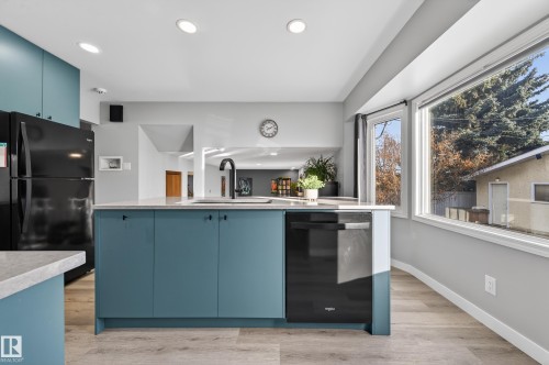 Kitchen with blue cabinetry, black appliances, light wood finished floors, recessed lighting, and light stone counters - 9215 Ottewell Road, Edmonton, AB - Indoor Photo Showing Kitchen