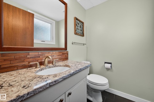Half bathroom featuring decorative backsplash, vanity, and dark tile patterned flooring - 9215 Ottewell Road, Edmonton, AB - Indoor Photo Showing Bathroom