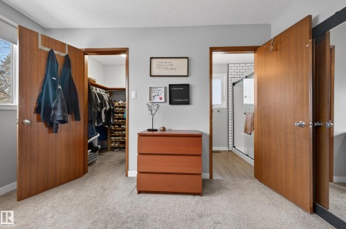 Bedroom featuring a spacious closet, light carpet, and a textured ceiling - 9215 Ottewell Road, Edmonton, AB - Indoor