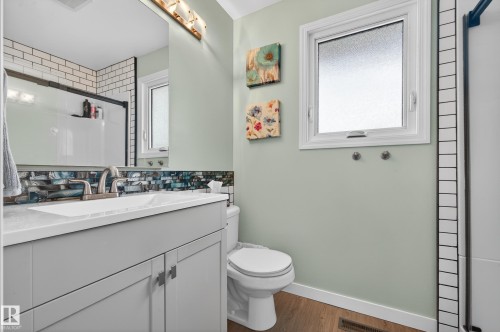 Full bathroom with a shower stall, vanity, backsplash, and wood finished floors - 9215 Ottewell Road, Edmonton, AB - Indoor Photo Showing Bathroom