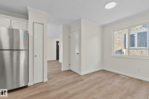 Unfurnished dining area with ornamental molding, light wood-style floors, and a textured ceiling - 4631 126 Avenue, Edmonton, AB - Indoor Photo Showing Other Room