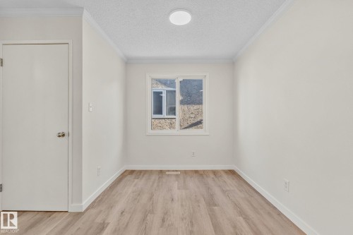 Unfurnished room with light wood-style floors, a textured ceiling, and ornamental molding - 4631 126 Avenue, Edmonton, AB - Indoor Photo Showing Other Room