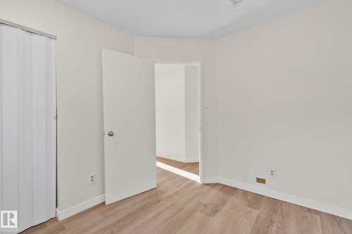 Unfurnished bedroom featuring light wood-style flooring, a closet, and a textured ceiling - 4631 126 Avenue, Edmonton, AB - Indoor Photo Showing Other Room