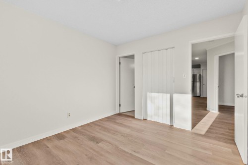 Unfurnished bedroom featuring light wood-style flooring and freestanding refrigerator - 4631 126 Avenue, Edmonton, AB - Indoor Photo Showing Other Room