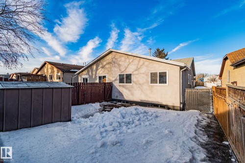 Snow covered property featuring stucco siding, a fenced backyard, a gate, and a shed - 4631 126 Avenue, Edmonton, AB - Outdoor