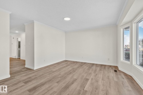 Empty room with crown molding, light wood-style floors, and a textured ceiling - 4631 126 Avenue, Edmonton, AB - Indoor Photo Showing Other Room