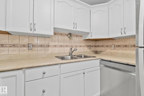 Kitchen featuring white cabinetry, stainless steel appliances, light countertops, and backsplash - 4631 126 Avenue, Edmonton, AB - Indoor Photo Showing Kitchen With Double Sink