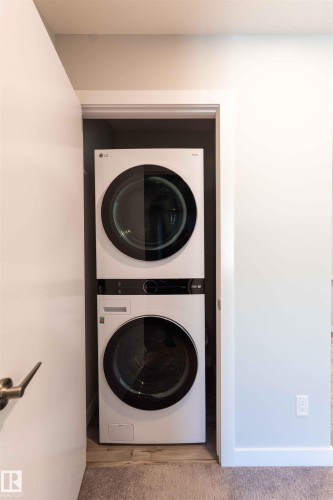 Washroom featuring stacked washer / dryer and baseboards - 21 1729 Keene Crescent, Edmonton, AB - Indoor Photo Showing Laundry Room