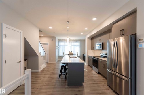 Kitchen with gray cabinets, stainless steel appliances, a kitchen island with sink, hanging light fixtures, and recessed lighting - 21 1729 Keene Crescent, Edmonton, AB - Indoor Photo Showing Kitchen With Upgraded Kitchen