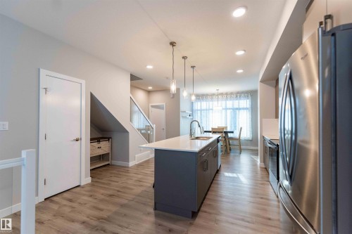 Kitchen featuring appliances with stainless steel finishes, a kitchen island with sink, hanging light fixtures, light wood finished floors, and gray cabinets - 21 1729 Keene Crescent, Edmonton, AB - Indoor Photo Showing Kitchen With Upgraded Kitchen