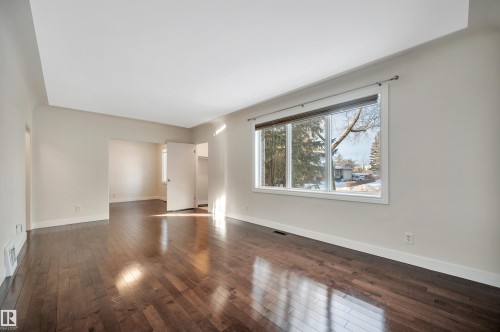 Unfurnished living room featuring dark wood-type flooring and baseboards - 6803 112A Street, Edmonton, AB - Indoor Photo Showing Other Room