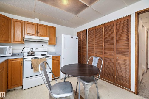 Kitchen featuring light floors, white appliances, wood finish cabinetry, and a drop ceiling - 12117 91 Street, Edmonton, AB - Indoor Photo Showing Kitchen