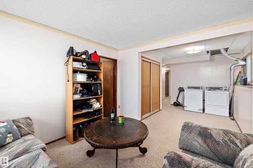 Sitting room featuring washer and clothes dryer, a textured ceiling, and light colored carpet - 12117 91 Street, Edmonton, AB - Indoor