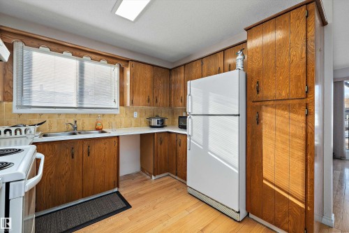 Kitchen featuring light countertops, white appliances, light wood-type flooring, and wood finish cabinetry - 12117 91 Street, Edmonton, AB - Indoor Photo Showing Kitchen With Double Sink