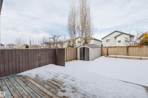 Yard covered in snow featuring a residential view, a shed, a fenced backyard, and a deck - 8420 Sloane Crescent, Edmonton, AB - Outdoor