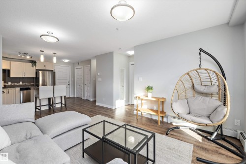 Living room with dark wood-type flooring and baseboard heating - 205 8515 99 Street, Edmonton, AB - Indoor Photo Showing Living Room