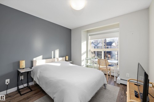 Bedroom with dark wood-style floors and a baseboard radiator - 205 8515 99 Street, Edmonton, AB - Indoor Photo Showing Bedroom