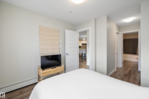Bedroom featuring dark wood-style flooring, baseboard heating, and connected bathroom - 205 8515 99 Street, Edmonton, AB - Indoor Photo Showing Bedroom