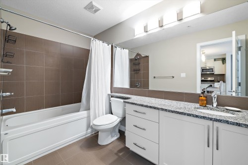 Bathroom with vanity, dark tile patterned flooring, and shower / tub combo with curtain - 205 8515 99 Street, Edmonton, AB - Indoor Photo Showing Bathroom