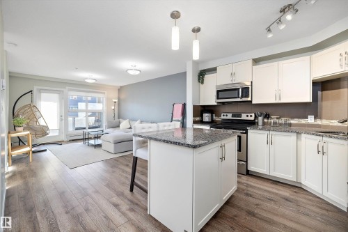 Kitchen featuring stainless steel appliances, a kitchen breakfast bar, open floor plan, white cabinetry, and pendant lighting - 205 8515 99 Street, Edmonton, AB - Indoor Photo Showing Kitchen With Stainless Steel Kitchen With Upgraded Kitchen
