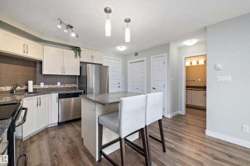 Kitchen featuring stainless steel appliances, white cabinetry, a center island, a kitchen breakfast bar, and hanging light fixtures - 205 8515 99 Street, Edmonton, AB - Indoor Photo Showing Kitchen With Stainless Steel Kitchen With Double Sink With Upgraded Kitchen