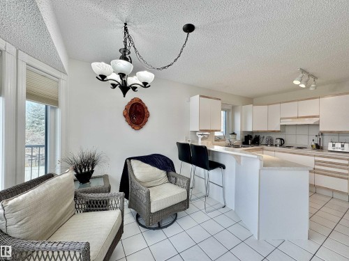 Kitchen featuring light countertops, a chandelier, a peninsula, a breakfast bar area, and white cabinets - 3772 30 Street, Edmonton, AB - Indoor Photo Showing Kitchen