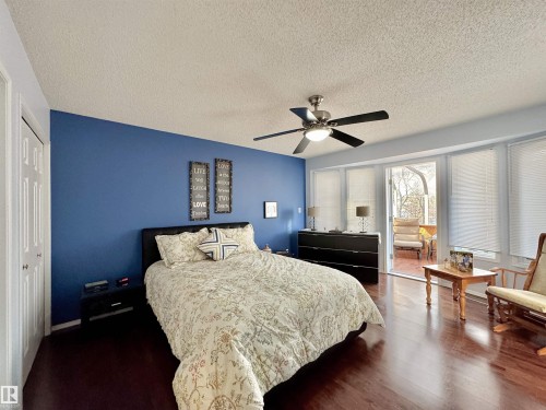 Bedroom with dark wood-type flooring, access to exterior, a textured ceiling, a closet, and ceiling fan - 3772 30 Street, Edmonton, AB - Indoor Photo Showing Bedroom