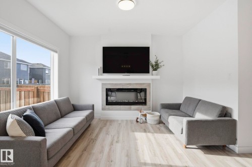 Living area featuring wood finished floors and a tiled fireplace - 16627 31 Avenue, Edmonton, AB - Indoor Photo Showing Living Room With Fireplace