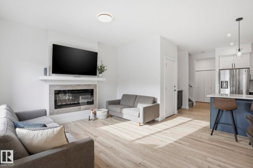 Living area featuring light wood-style floors, a tile fireplace, and recessed lighting - 16627 31 Avenue, Edmonton, AB - Indoor Photo Showing Living Room With Fireplace