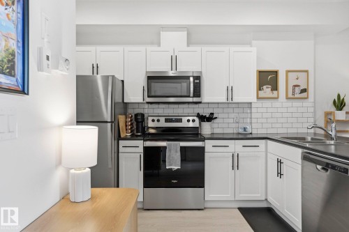 Kitchen featuring stainless steel appliances, white cabinets, backsplash, and light wood-style flooring - 16627 31 Avenue, Edmonton, AB - Indoor Photo Showing Kitchen With Double Sink With Upgraded Kitchen