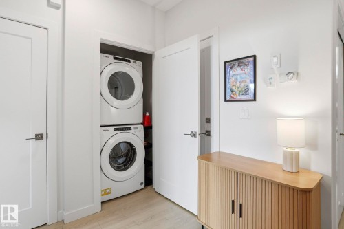 Laundry area with light wood finished floors and stacked washer and clothes dryer - 16627 31 Avenue, Edmonton, AB - Indoor Photo Showing Laundry Room