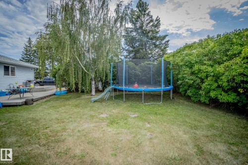 View of green lawn featuring a deck and a trampoline - 56430 Range Rd 113, Rural St. Paul County, AB - Outdoor