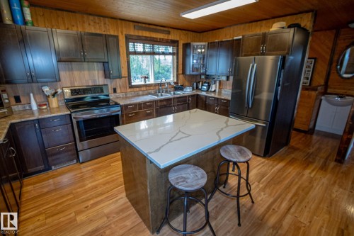 Kitchen with stainless steel appliances, a kitchen bar, a kitchen island, light wood-style floors, and wood ceiling - 56430 Range Rd 113, Rural St. Paul County, AB - Indoor Photo Showing Kitchen With Double Sink